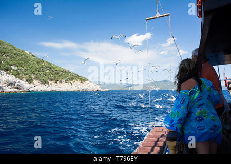 Neos Marmaras, Halkidiki, Greece - June 29, 2014: Tourists on a pleasure boat feed seagulls near the Chalkidiki peninsula Туристы кормят чаек. Греция Stock Photo