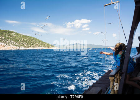 Neos Marmaras, Halkidiki, Greece - June 29, 2014: Tourists on a pleasure boat feed seagulls near the Chalkidiki peninsula Туристы кормят чаек. Греция Stock Photo