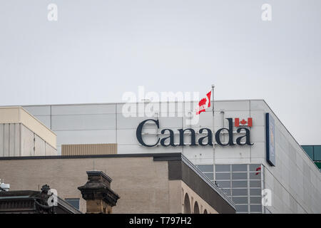 OTTAWA, CANADA - NOVEMBER 12, 2018: Canada Wordmark, the official logo of the Canadian government, on an administrative building next to a Canadian fl Stock Photo