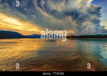 Monsoon clouds/storm clouds at dusk over Umiam lake, also known as Barapani lake. Beautiful colours cast by setting sun. Shillong, Meghalaya, India. Stock Photo