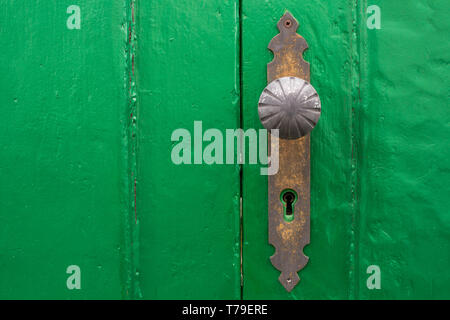 Wooden gate painted green, which is traditional color of the area. Old brass handle with a big keyhole. Arico Nuevo, Tenerife, Canary Islands, Spain. Stock Photo