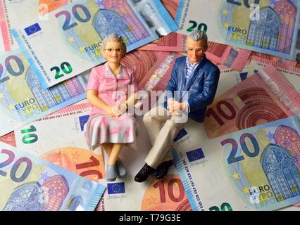 Married pensioner couple, with euro notes blurred in the background. money retirement concept Stock Photo