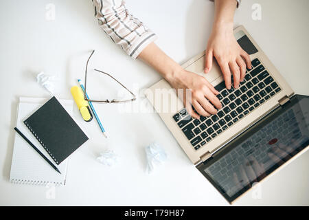 Top view of female hands working behind a laptop in a working office or home office. Or the student does the lessons or exercises. Stock Photo