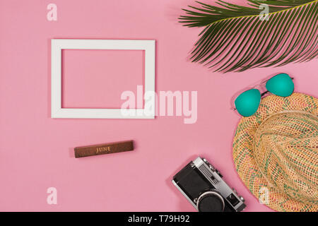 Stylish summer composition with photo frame, green leaves, hat and sunglasses on a blue pastel background. Artwork mockup with copy space Stock Photo