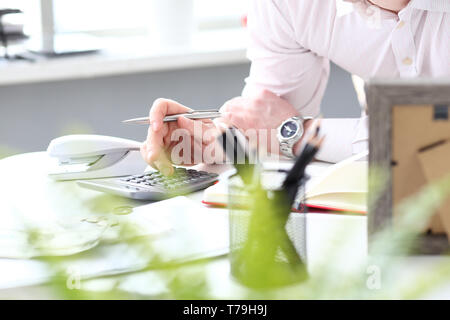 Hand of male clerk hold silver pen using calculator evaluating expenses Stock Photo
