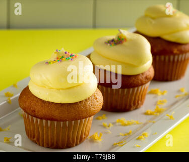 Three Yellow Cupcakes with Lemon Frosting on a White Plate Stock Photo