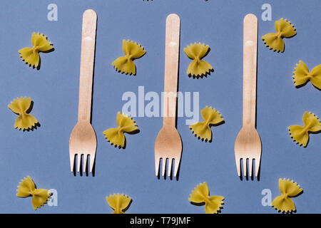three forks among macaroni isolated on the blue background, top view, creativity , experiment Stock Photo