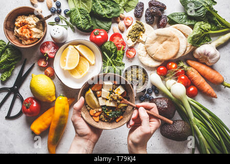 Healthy vegetarian food background. Vegetables, hummus, pesto and lentil curry with tofu. Stock Photo