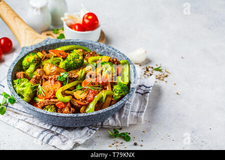 Fried beef stroganoff with potatoes, broccoli, corn, pepper, carrots and sauce in a pan, white background. Stock Photo