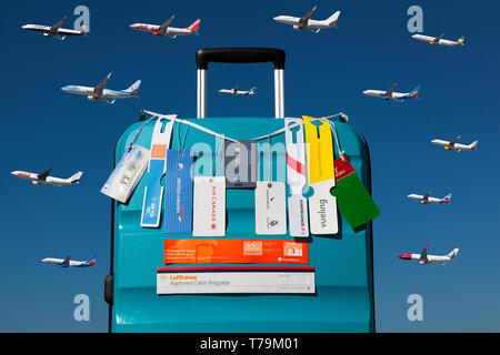 Trolley with hand luggage tags of different airlines over a blue sky with several airplanes Stock Photo