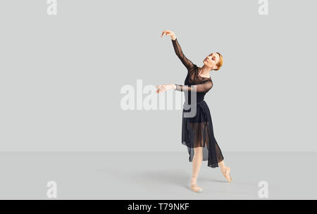 Ballerina dancer in black dress on a gray background. Stock Photo