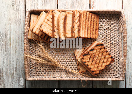 Wicker tray with toasted bread on wooden table Stock Photo