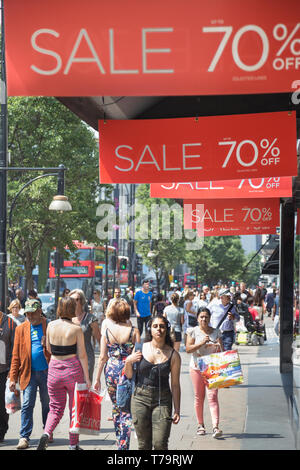 Shoppers on Oxford Street in the West End of London walk past summer Sale sign at House of Fraser flagship store Stock Photo
