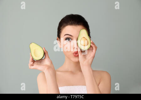 Funny young woman with avocado on color background Stock Photo