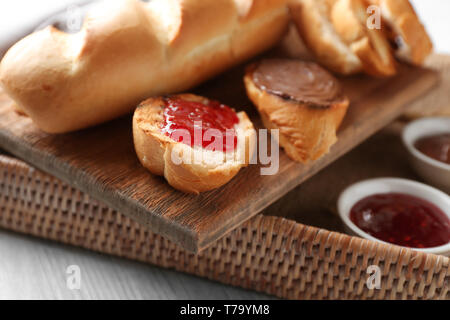 Wicker tray with delicious toasts, jam and chocolate paste on table Stock Photo