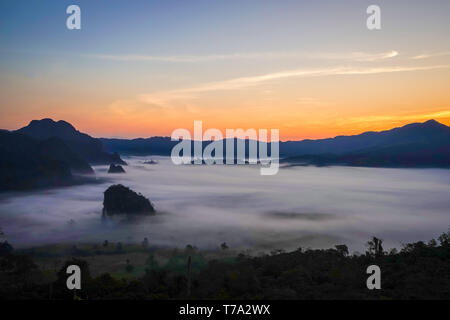 Sunrise in the morning behind mountain and fog below at Phu Langka, Phayao Province, North of Thailand. Stock Photo