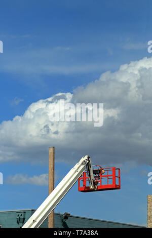 Cherry picker crane and hydraulic construction cradle with white clouds and blue sky on background Stock Photo