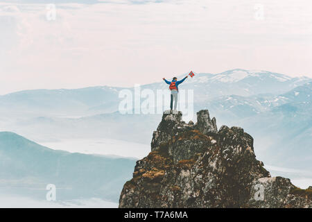 Man on mountain summit adventure climbing extreme active lifestyle vacations outdoor in Norway success raised hands emotions Stock Photo