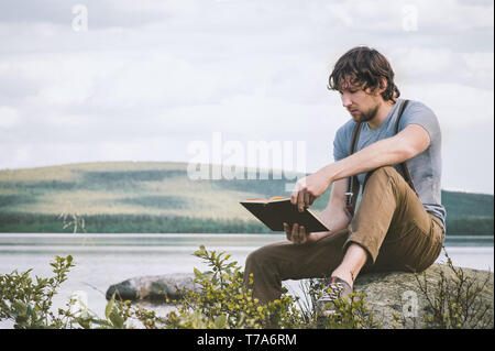 Student man reading book outdoor self education summer vacations lifestyle Stock Photo