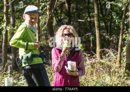 Mother with son geocaching in the forest with a found cache in hand Stock Photo