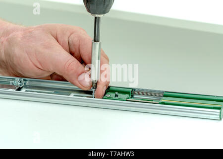 Assembling furniture from chipboard, using a cordless screwdriver, close up Stock Photo