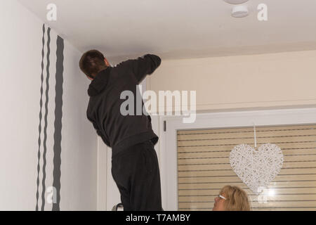 The man drills a hole in the ceiling before mounting a curtain rod Stock Photo