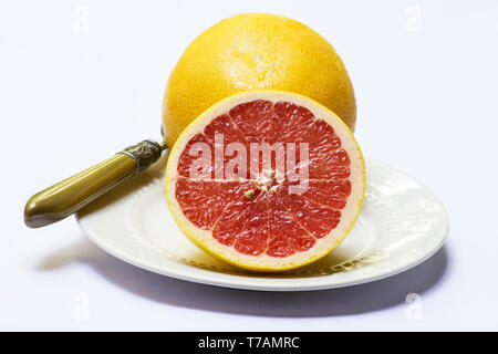 Whole and half grapefruit in a plate on white background Stock Photo