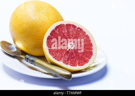 Whole and half grapefruit in a plate on white background Stock Photo
