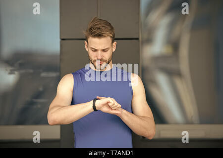 Set up route. Man athlete busy face check fitness tracker urban background. Athlete with bristle looks at fitness tracker or pedometer. Sportsman training with pedometer gadget. Sport gadget concept. Stock Photo