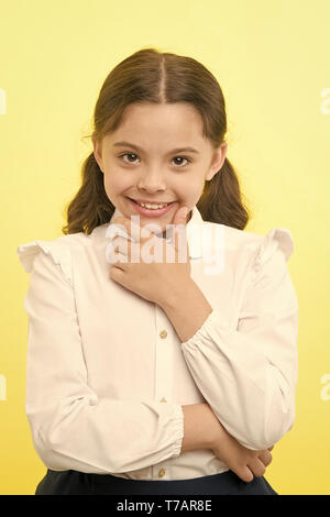 She is planning a prank. Girl school uniform smiling cunning face yellow background. Girl happy back to school. Child ready back to school end continue fun. Schoolgirl formal outfit looks cute. Stock Photo