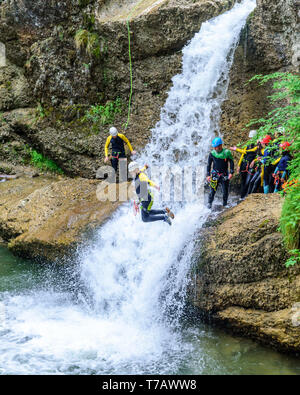 Audacious jumps into white water of a waterfall in a gorge during canyoning tour Stock Photo