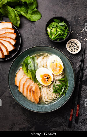 Chicken Ramen Soup In Bowl With Egg. Table Top View. Black Concrete Background. Asian Cuisine Stock Photo
