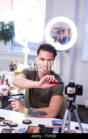Smiling good-looking young guy presenting new products on camera Stock Photo