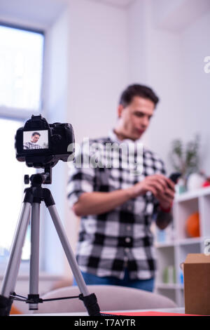 Dark-haired young man shooting new video for his channel Stock Photo
