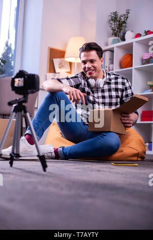 Beaming positive man sitting on the floor during shooting process
