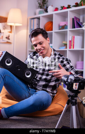Positive good-looking experienced blogger pointing on spacious speaker