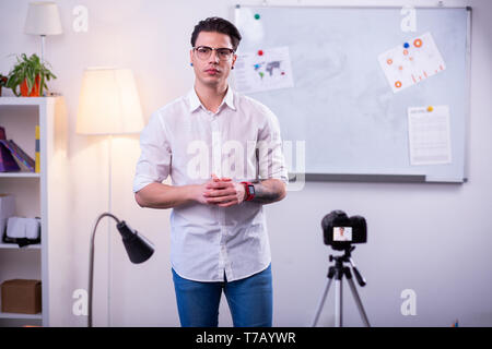 Elegant concentrated guy in clear glasses wearing white shirt