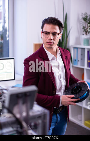 Interested good-looking young man working with complicated technique Stock Photo