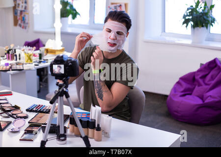 Curious communicative guy sitting in front of professional camera Stock Photo