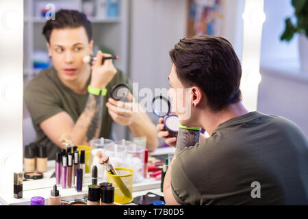 Curious handsome guy getting ready in front of mirror Stock Photo