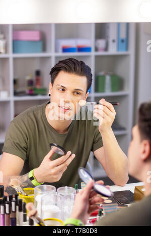 Calm good-looking young man being obsessed with makeup Stock Photo