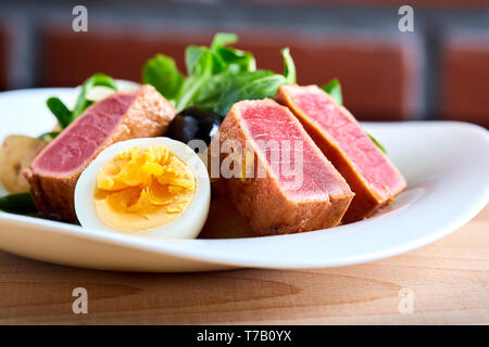 Nicoise salad with grilled tuna and boiled egg on a wooden background, close-up Stock Photo