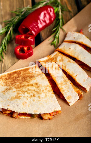 Mexican quesadilla with chicken, cheese and peppers on wooden table. Stock Photo