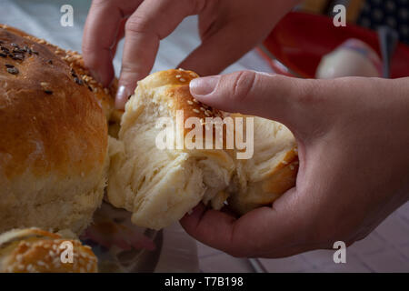 Woman hands breaking bread over the table on ortodox easter Stock Photo