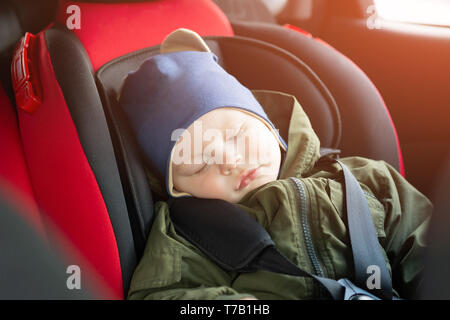 Close Up caucasian cute baby boy sleeping in modern car seat. Child traveling safety on the road. Safe way to travel fastened seat belts in a vehicle 