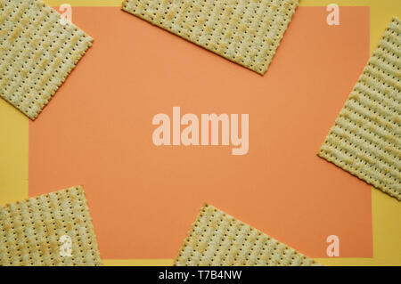 Five pieces of Matzo on the coral and yellow background. Empty space for text. Trendy concept. Stock Photo