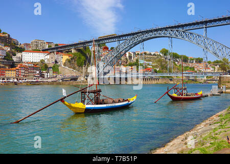 The Dom Luis I metal arch bridge over the Douro River and boats for transporting port wine casks in Porto, Portugal Stock Photo