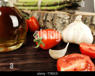 tomatoes, olive oil, asparagus and garlic on dark wood table Stock Photo