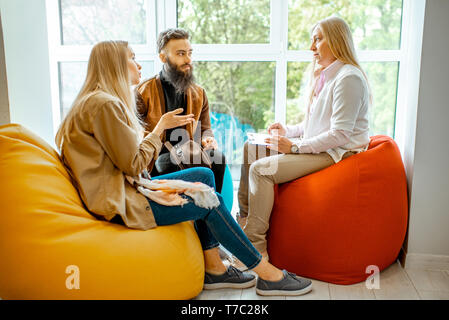 Young couple having misunderstandings during the psychological counseling with senior female psychologist in the office Stock Photo
