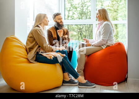 Young couple having misunderstandings during the psychological counseling with senior female psychologist in the office Stock Photo